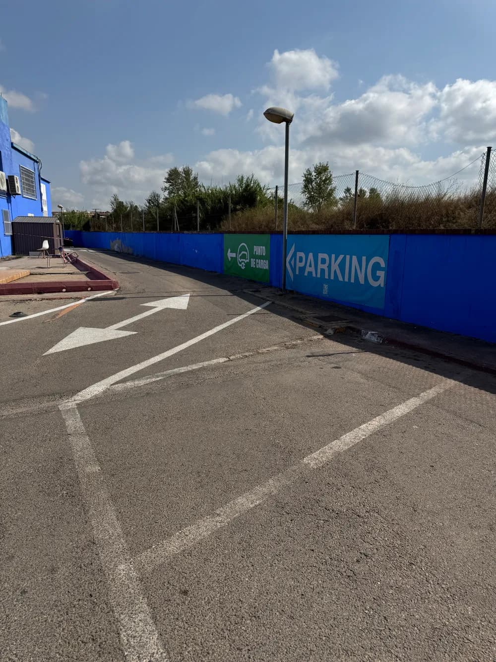 Cartel verde de punto de carga con una flecha, en la pared del parking de Tenisquash